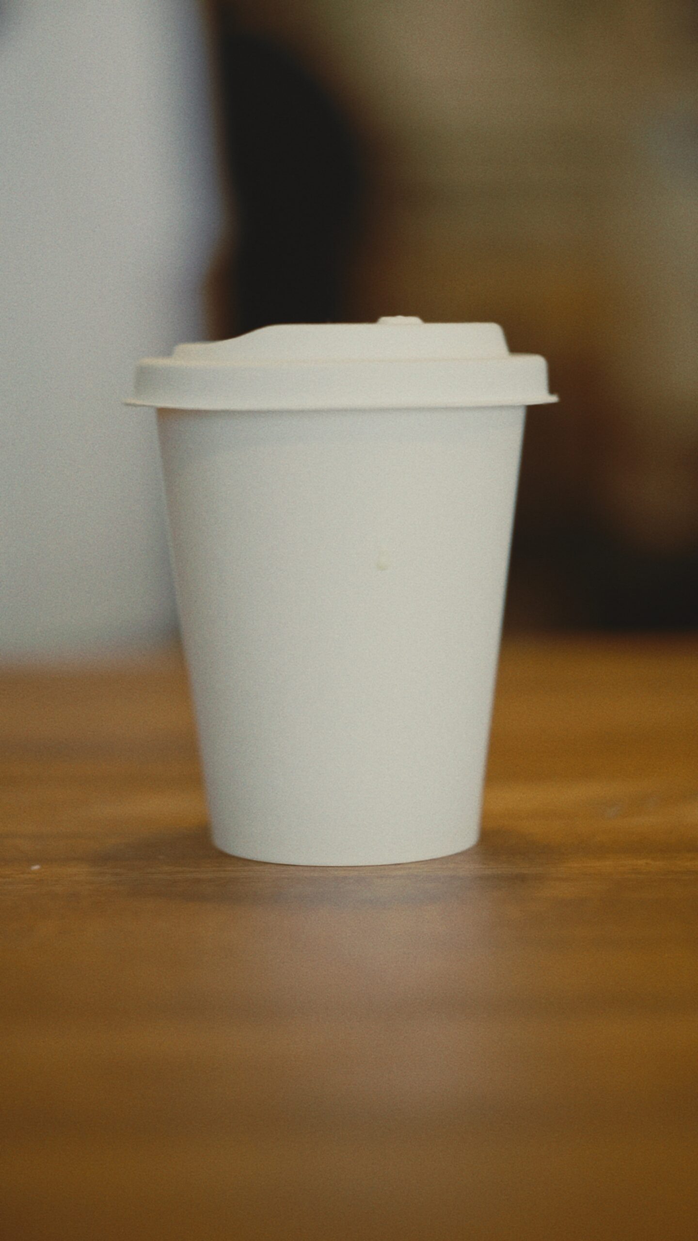 A Just Paper cup of flat white with latte art on a cafe table